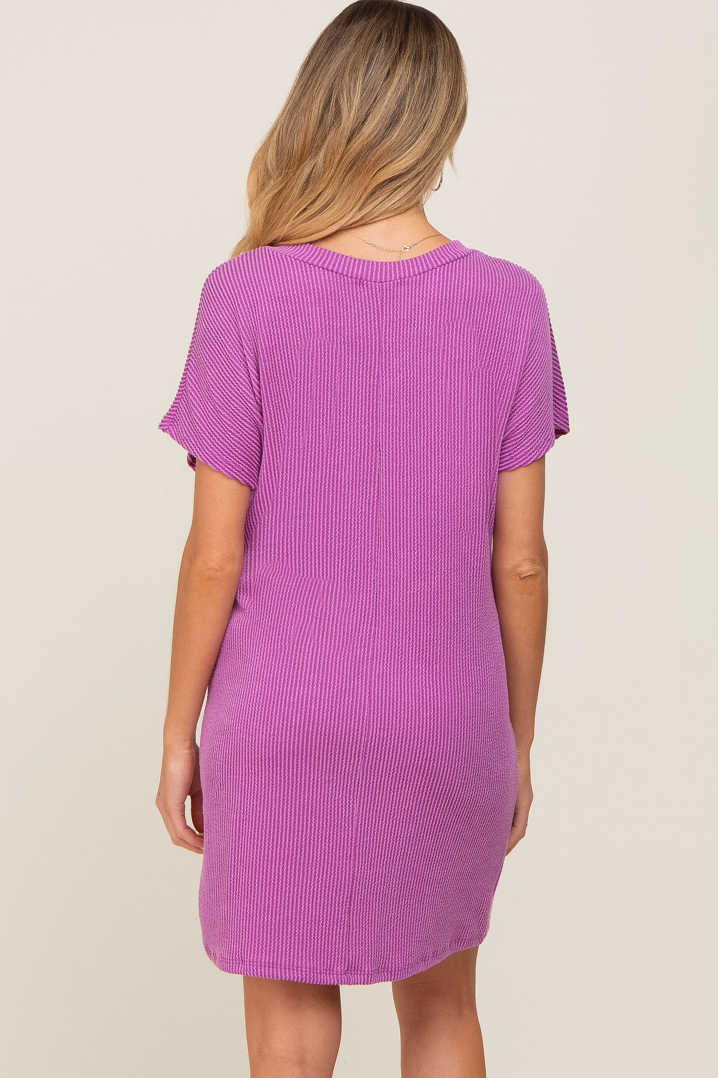 woman wearing a pink ribbed maternity dress with short sleeves, shown from the back