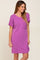 woman wearing a short sleeve loose fit purple ribbed dress with a front pocket