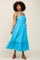 Woman with curly hair wearing a bright blue sleeveless midi dress with a pleated bodice and tiered skirt
