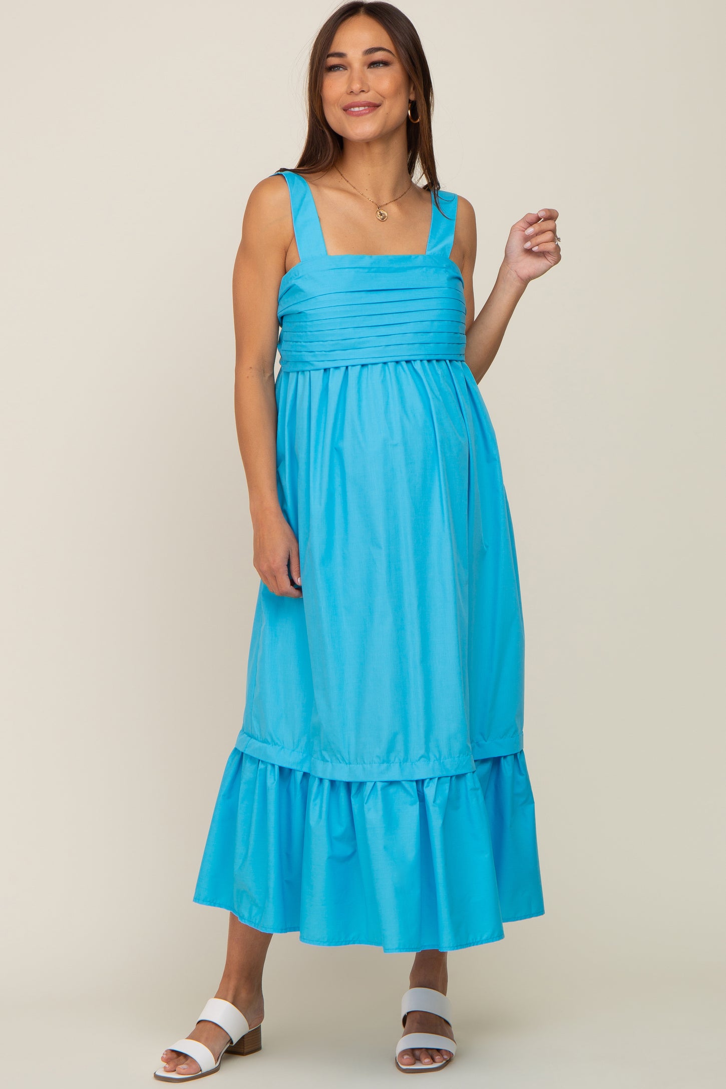 woman wearing a bright blue maternity dress with square neckline and ruffled hem, showcasing her baby bump