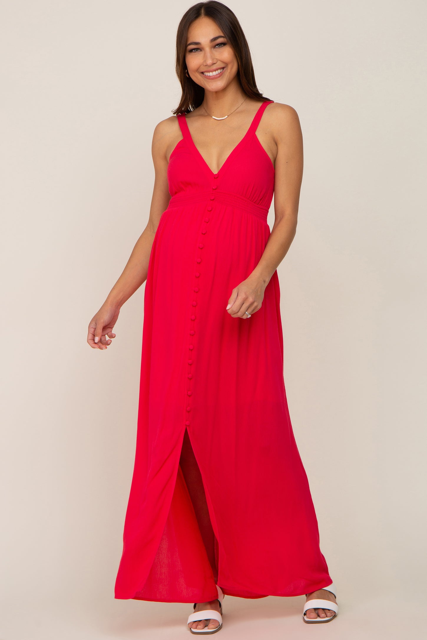 woman wearing a bright pink maternity maxi dress with a button-down front and a slit, showcasing her baby bump