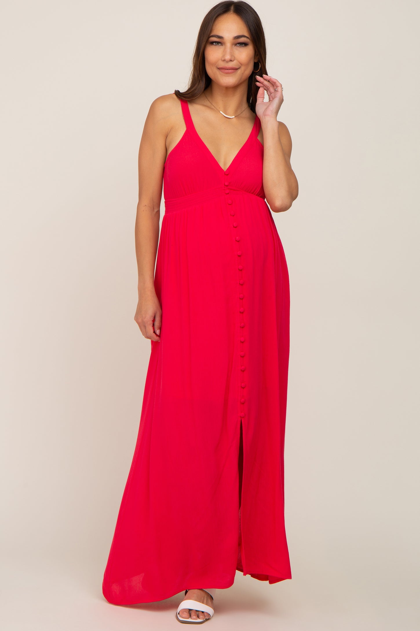 woman wearing a bright pink maternity maxi dress with a v-neckline and button detailing, showing her baby bump