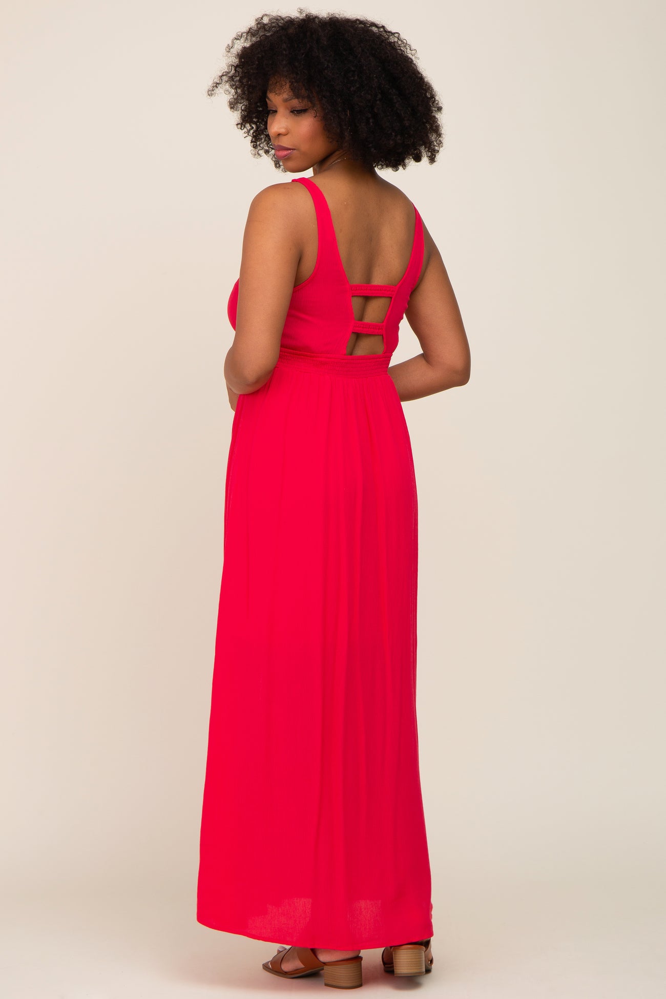 woman wearing a bright pink maxi dress with a scoop back and three strap details