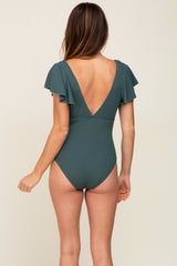 woman wearing a dark green ribbed one-piece swimsuit with flutter sleeves and a plunging back neckline