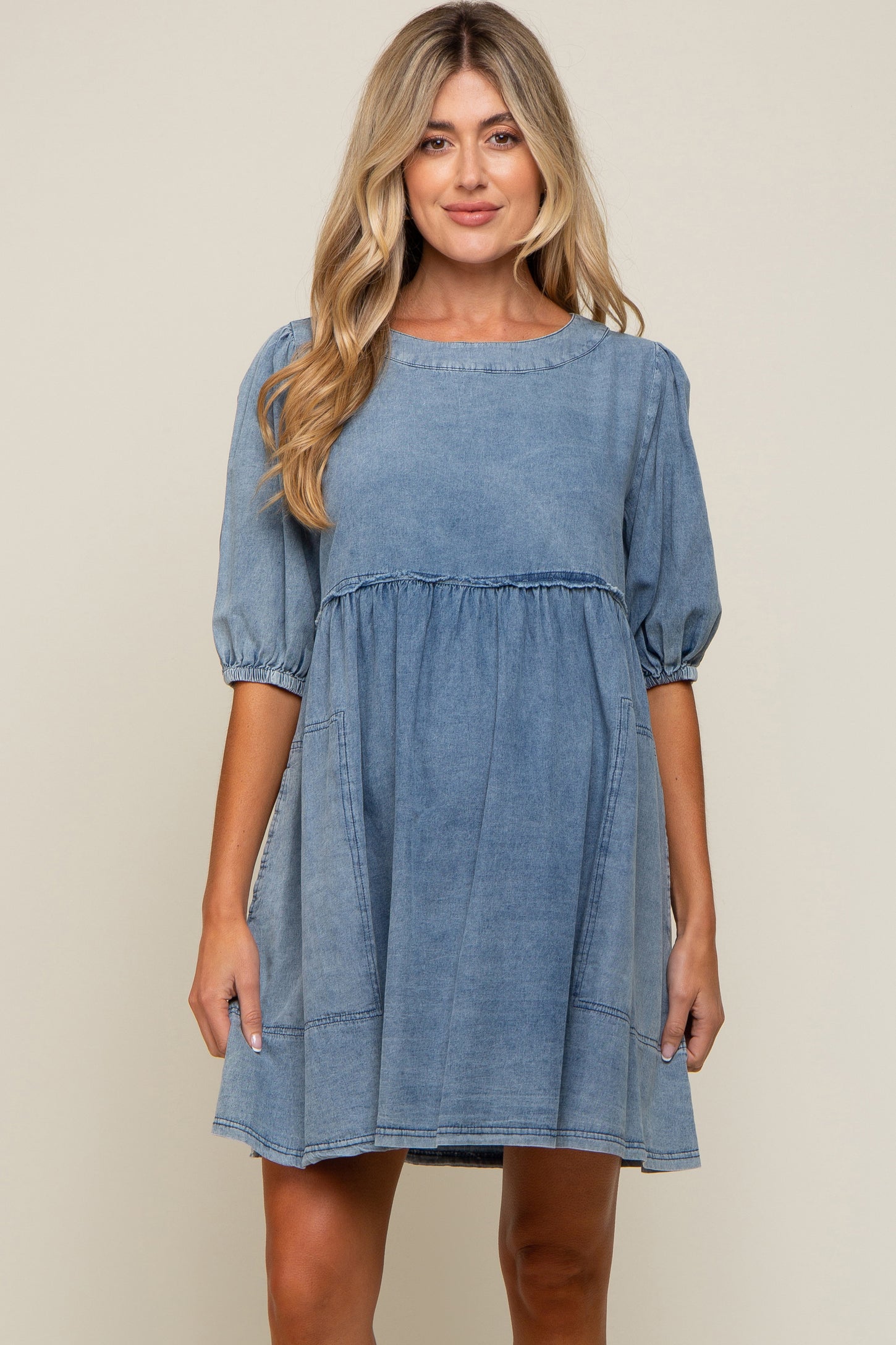 woman wearing a light blue short sleeve maternity dress with a gathered waist and puff sleeves