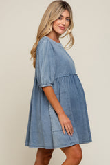 woman wearing a light blue denim maternity dress with short puff sleeves and a flowy skirt, showing her baby bump
