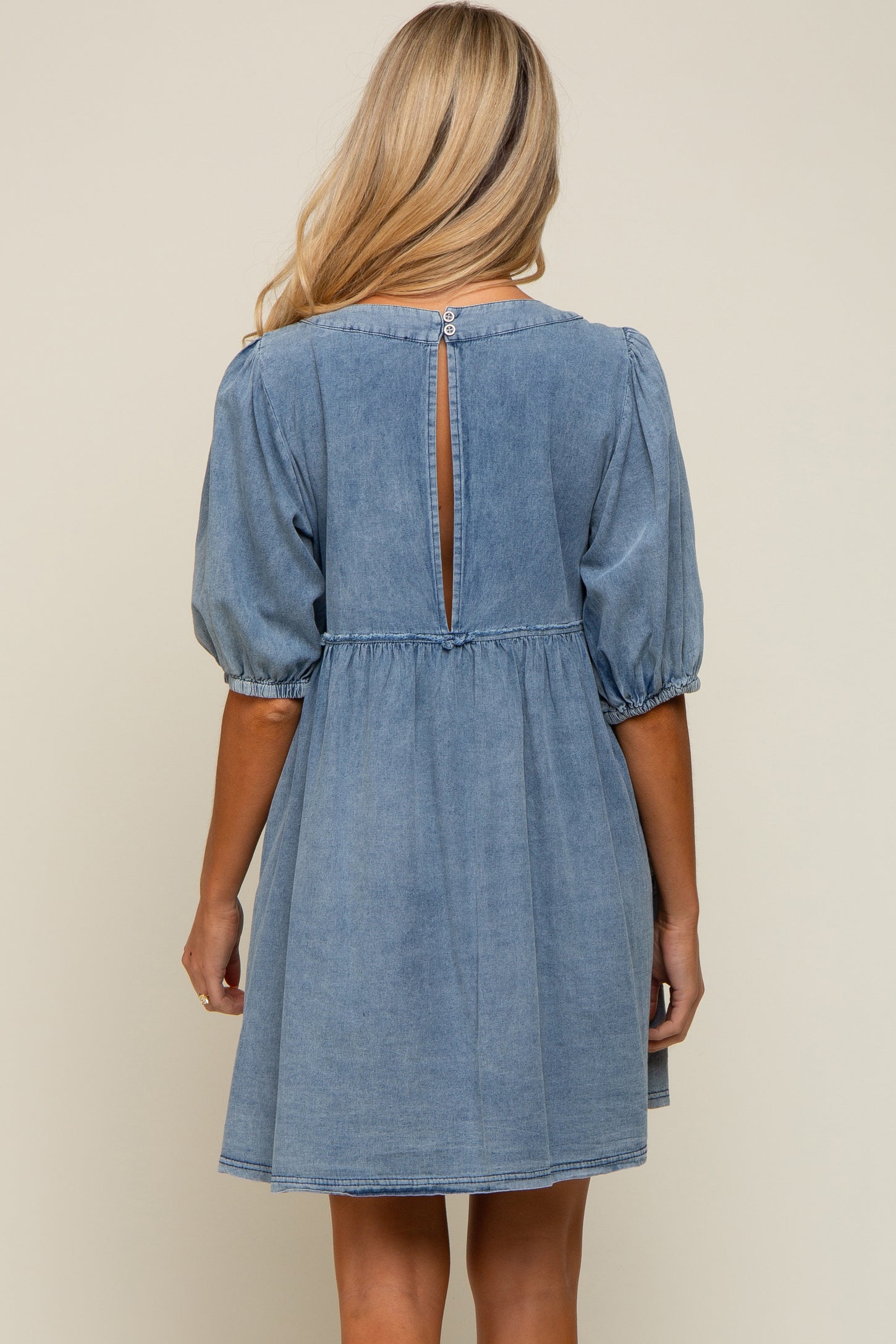 woman wearing a denim maternity dress with puff sleeves and a keyhole back detail