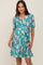 woman wearing a teal floral print maternity wrap dress with short sleeves and a waist tie