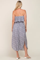 Back view of a woman wearing a blue floral strapless midi dress with a ruffled bodice and side slit