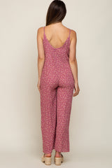 woman wearing a pink floral maternity jumpsuit with wide legs and thin straps, showing the back view