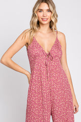 woman wearing a pink floral jumpsuit with a deep v-neck and adjustable straps