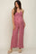 woman wearing a pink floral maternity jumpsuit with a tie front detail and a visible baby bump
