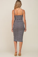 Back view of a woman wearing a black and white floral print midi dress with spaghetti straps and tan heels