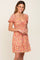 woman wearing an orange floral print mini dress with puff sleeves and a sweetheart neckline