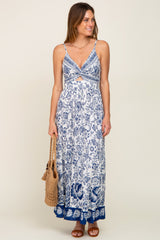 woman wearing a blue and white floral maxi dress with a straw bag and brown sandals