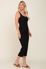 woman wearing a black fitted midi dress with spaghetti straps and a side slit, standing sideways