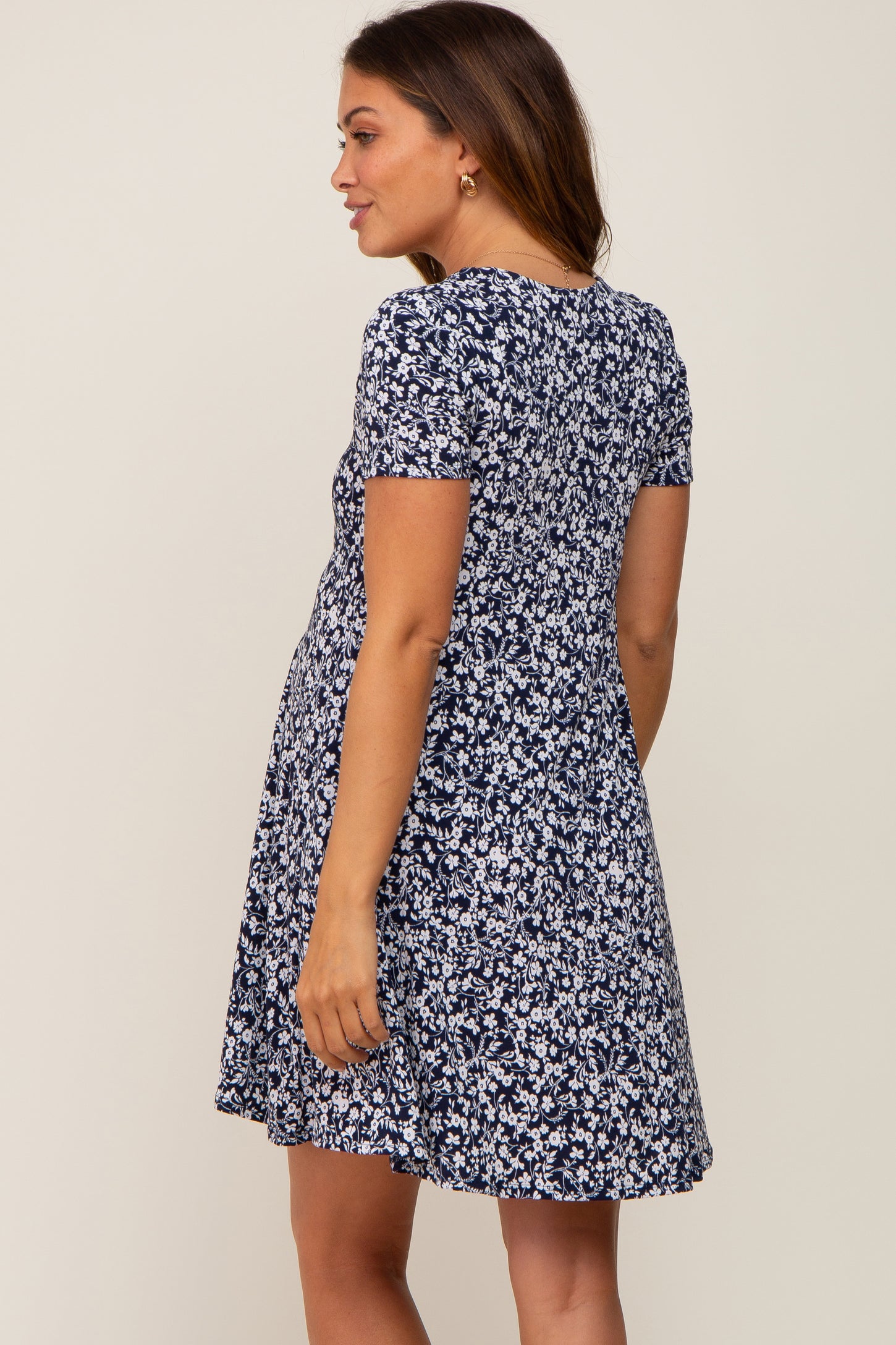 Woman wearing a navy blue and white floral print short sleeve maternity dress seen from the back