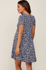 Woman wearing a navy blue and white floral print short sleeve maternity dress seen from the back