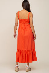 Back view of a woman wearing an orange sleeveless maxi dress with a smocked back and ruffled hem
