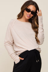 woman wearing a light beige maternity long sleeve top with relaxed fit and sunglasses, styled with black pants