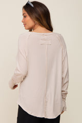 woman wearing a light beige long sleeve maternity top with a back button detail