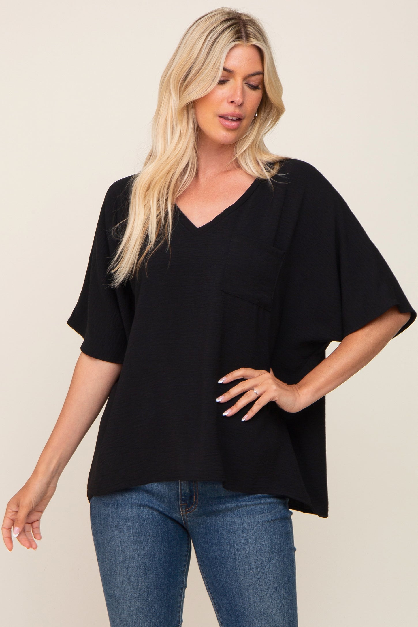 blonde woman wearing a black v-neck oversized pocket tee and blue jeans