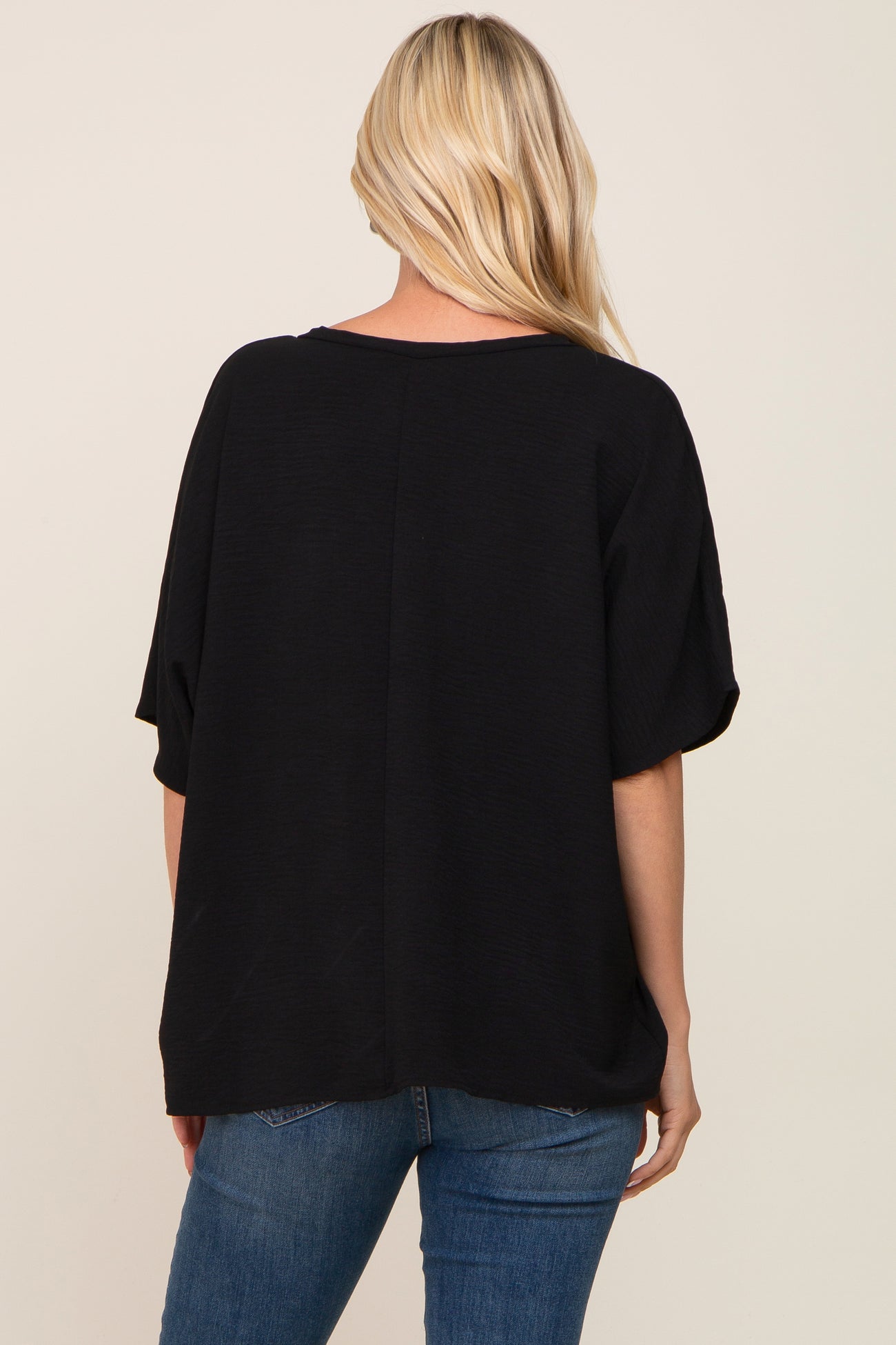 woman wearing a black oversized top with short sleeves and a relaxed fit, viewed from the back