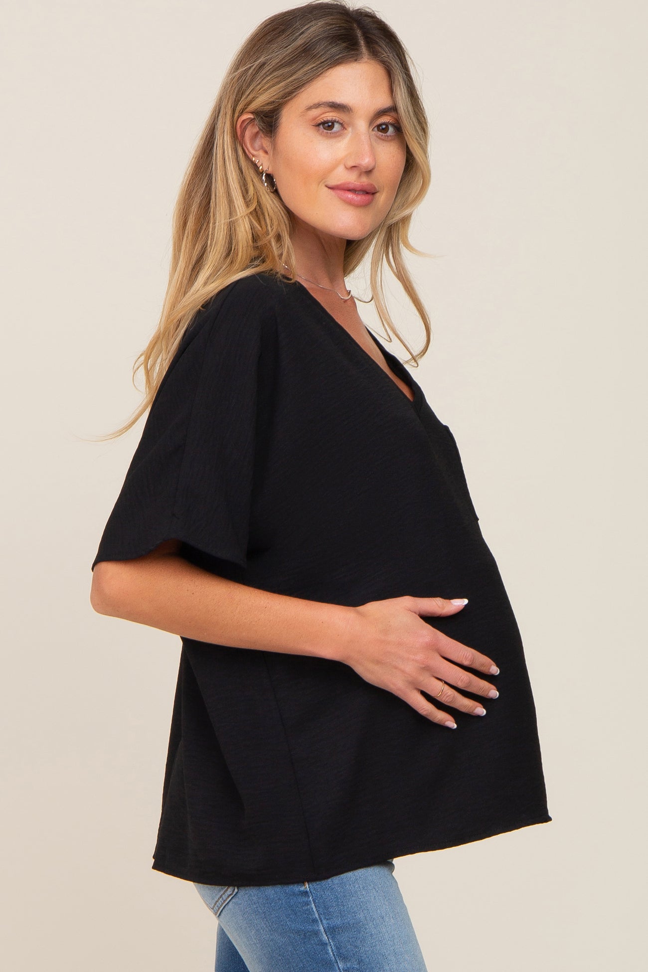 woman wearing a black short sleeve maternity top and holding her baby bump