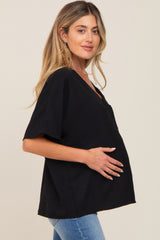 woman wearing a black short sleeve maternity top and holding her baby bump