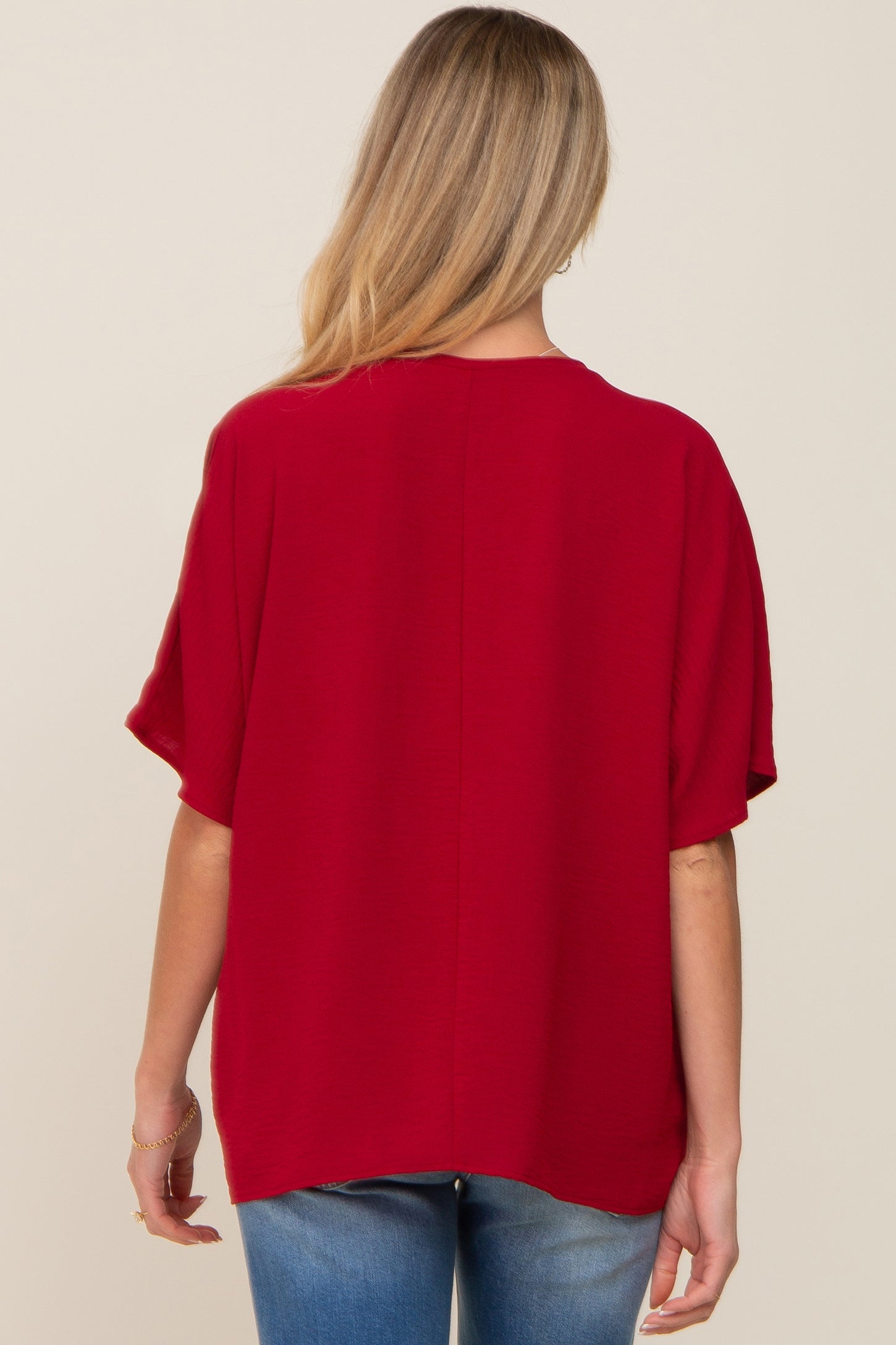woman wearing a red short sleeve maternity top from the back, showing a loose and relaxed fit
