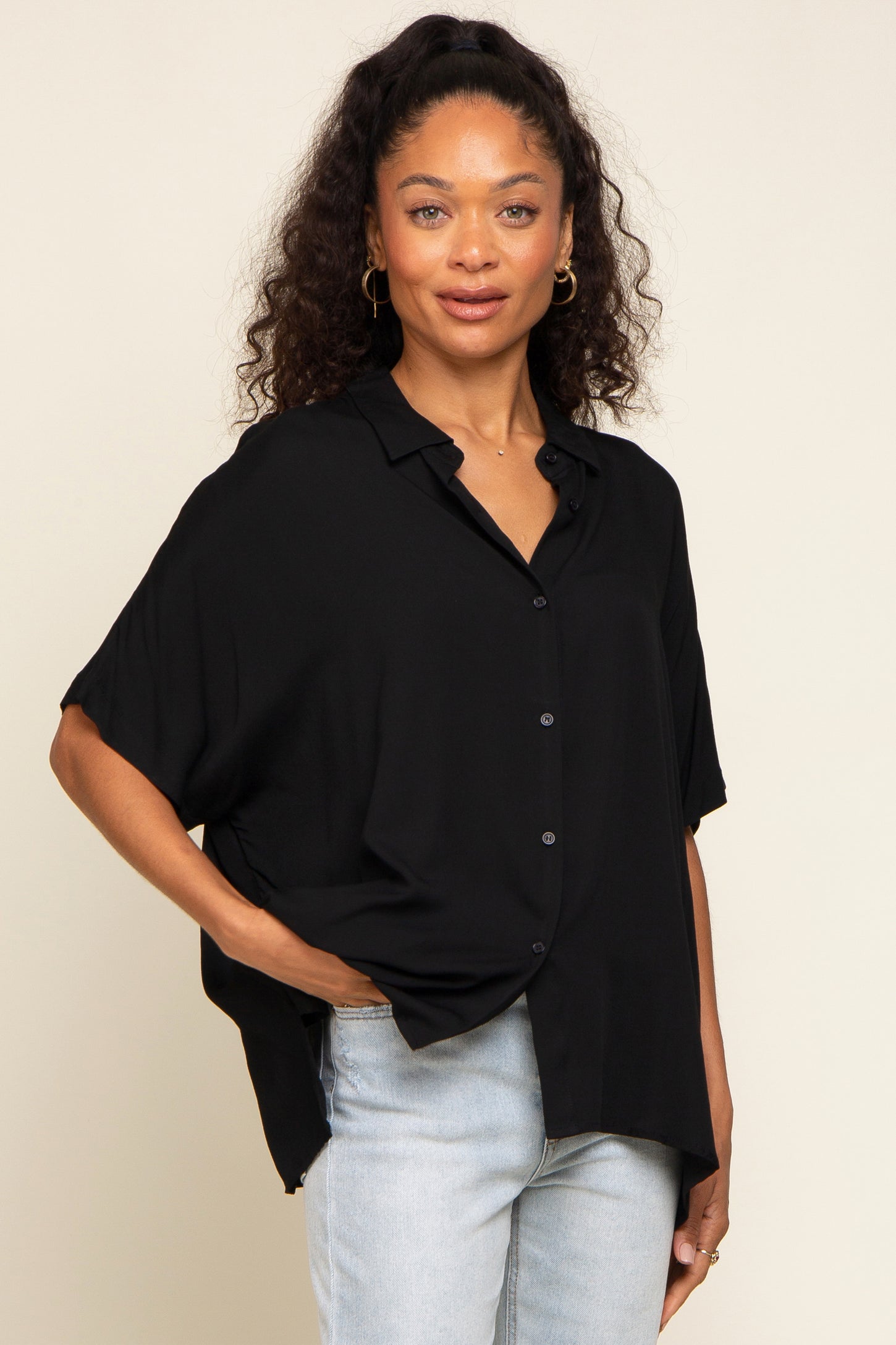 woman wearing a black button-up shirt with a relaxed fit and rolled short sleeves paired with light blue jeans