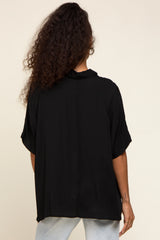 woman wearing a loose-fitting black blouse with short sleeves and a collar, seen from the back