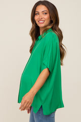 woman wearing a bright green oversized maternity top with short sleeves and a visible baby bump