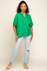 woman wearing a green oversized button-up shirt with rolled sleeves and light blue distressed jeans