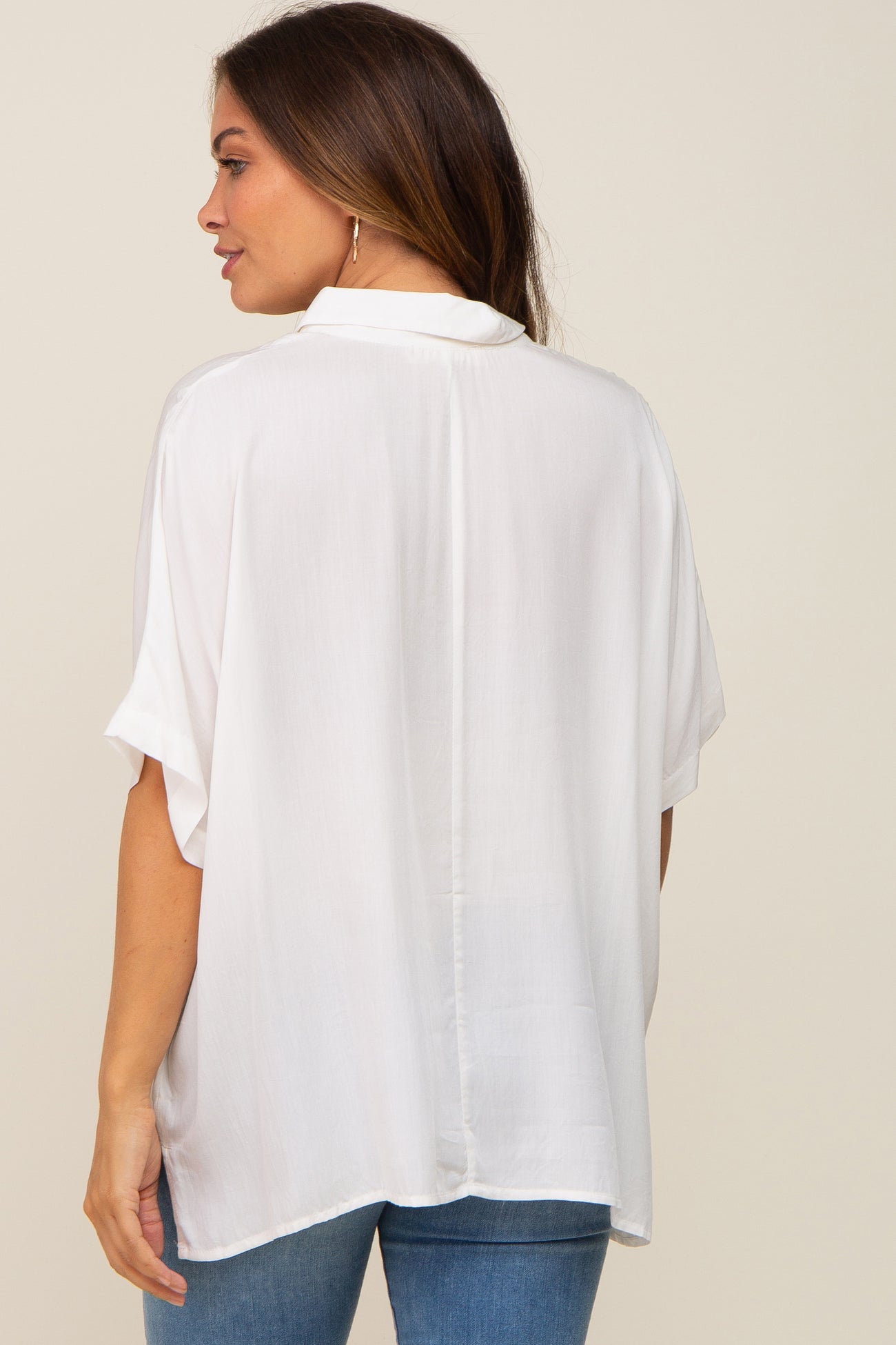 woman wearing a loose-fitting white maternity top with short sleeves and a relaxed back design