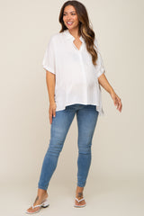 woman wearing a white short sleeve maternity top and blue skinny jeans, showing her baby bump