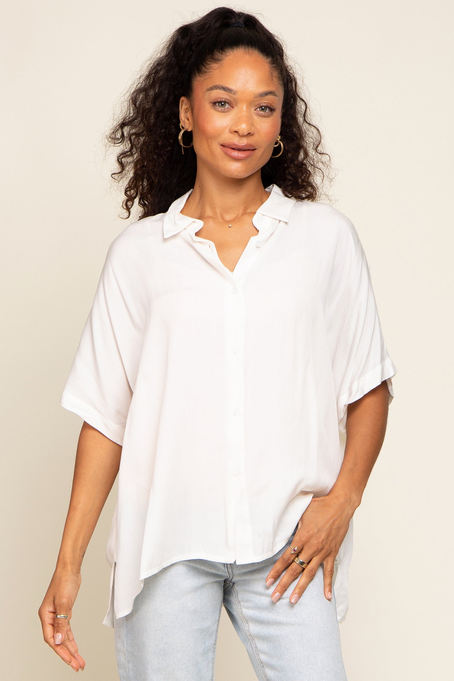woman wearing a loose-fitting white button-up shirt with rolled sleeves and light blue jeans