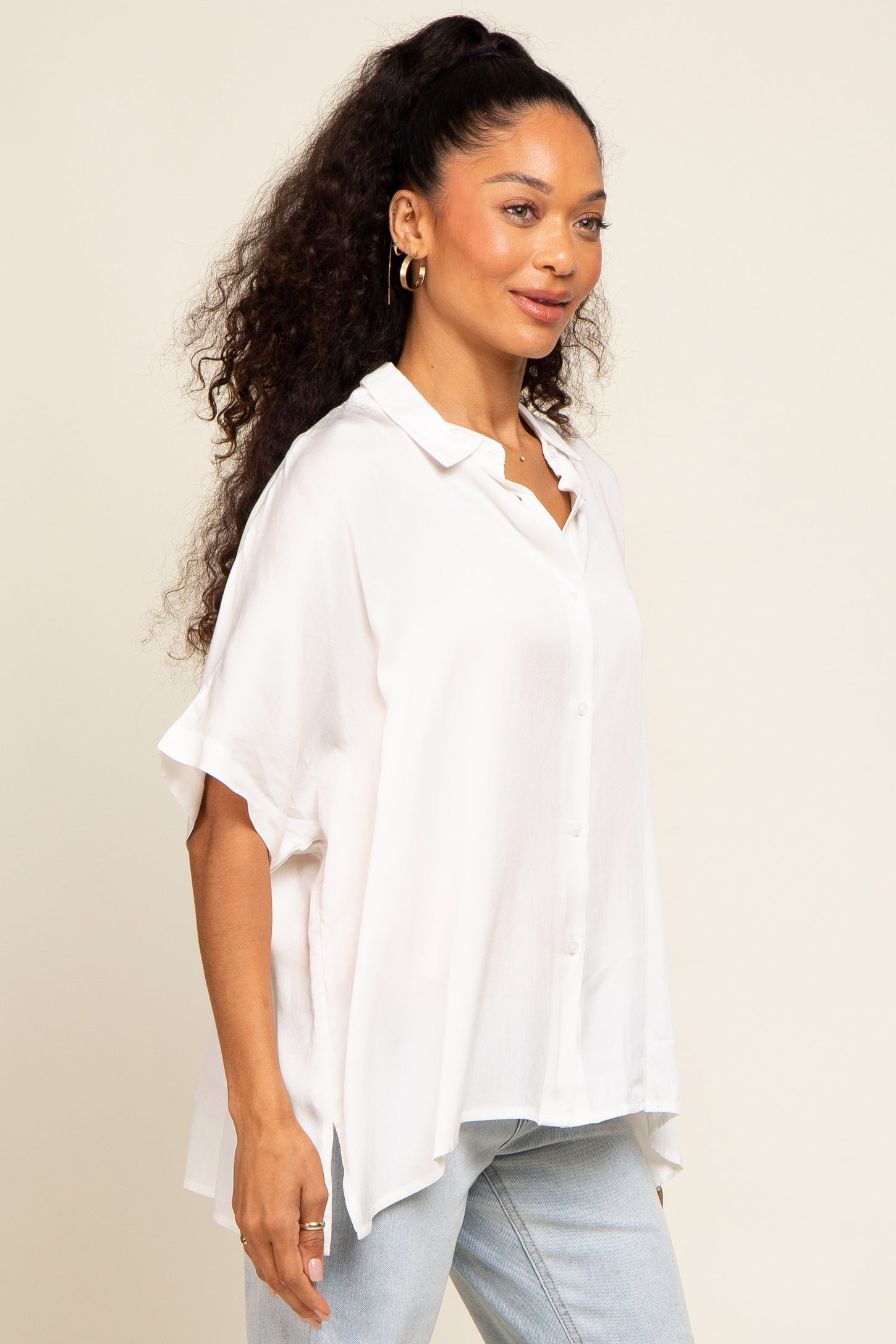woman wearing a white button-up shirt with loose sleeves and a relaxed fit, styled with light blue jeans