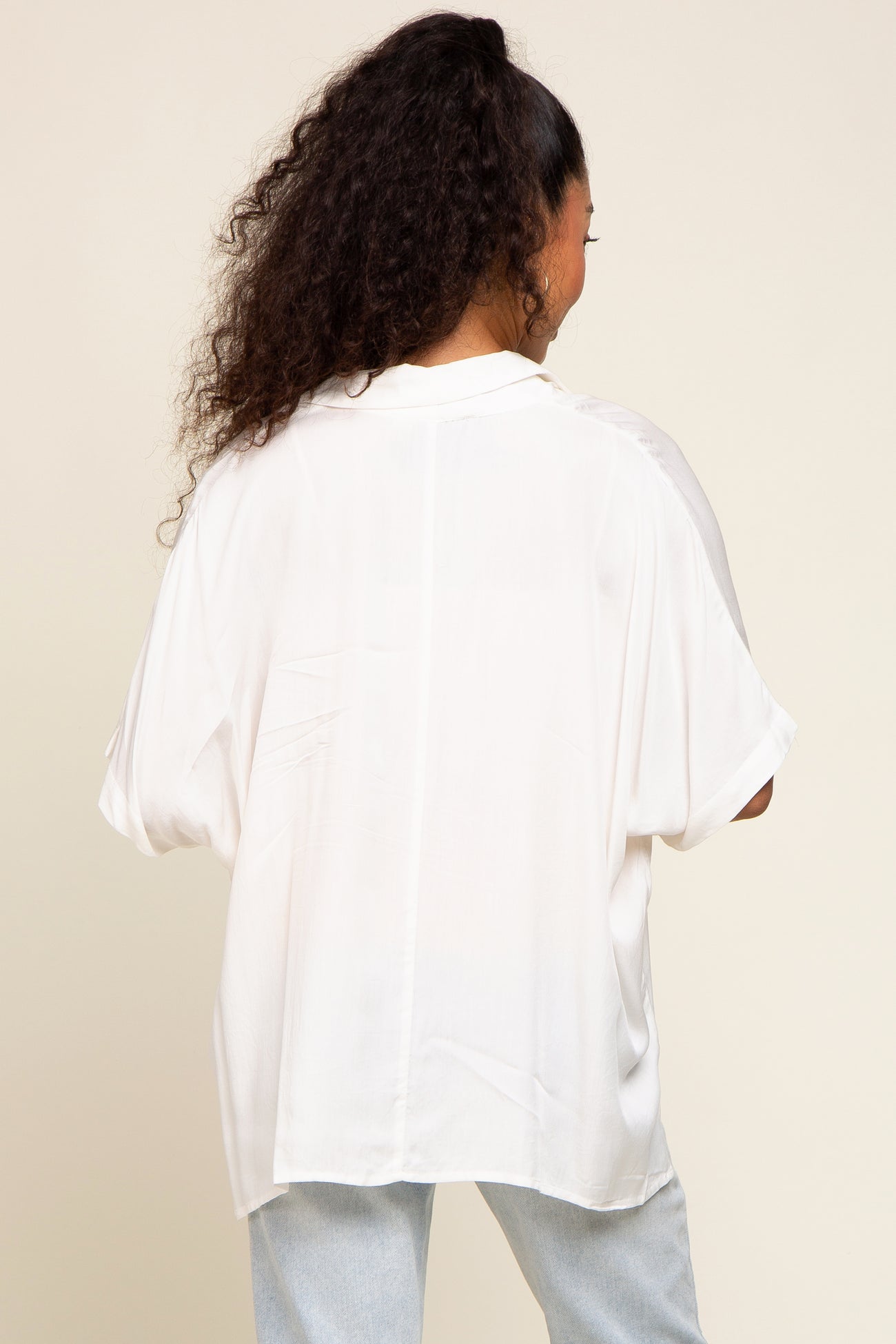 woman wearing a loose-fitting white blouse with short sleeves, viewed from the back.