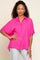 woman wearing a bright pink short sleeve button down shirt and light wash jeans