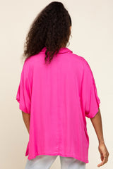 back view of a woman with curly hair wearing a bright pink short sleeve button down shirt and light wash jeans