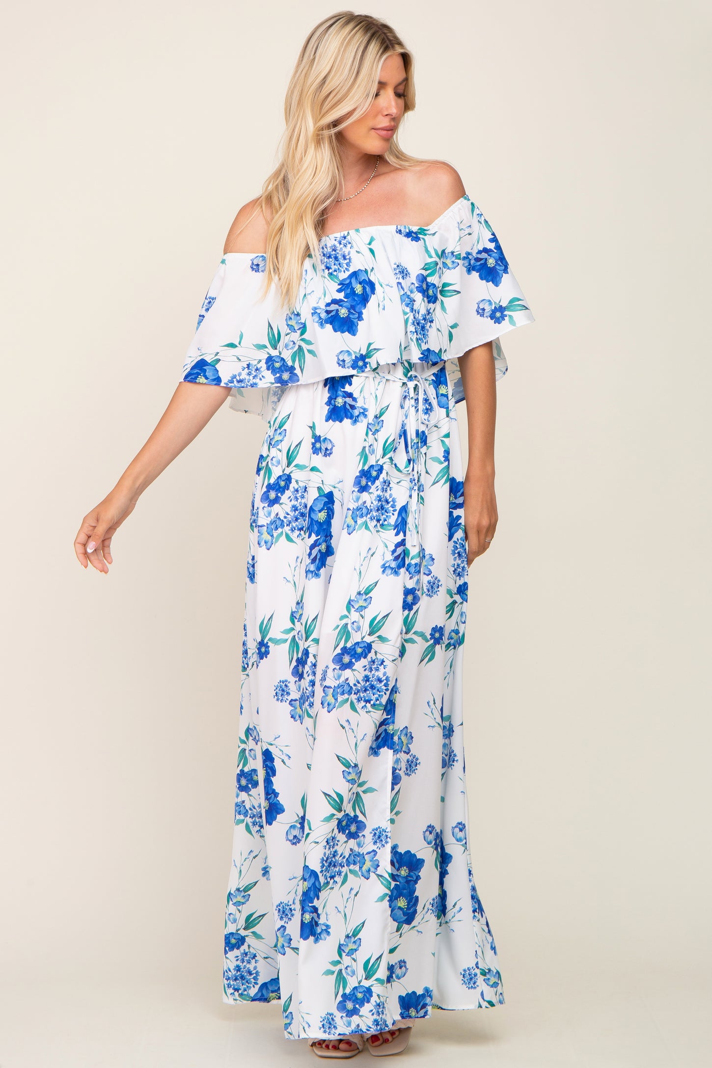 blonde woman wearing a white off-the-shoulder maxi dress with blue floral print