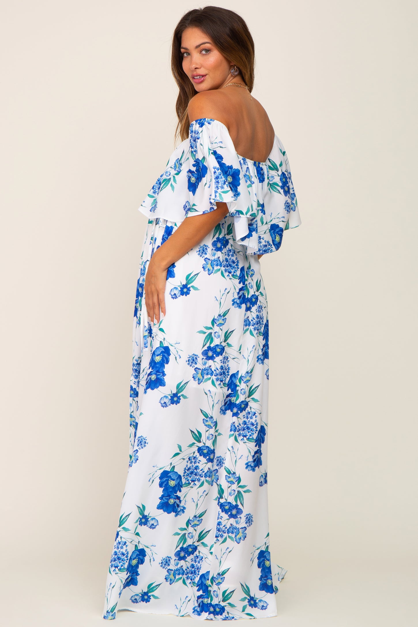 woman wearing a white off-the-shoulder maternity maxi dress with blue floral print