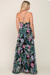 woman wearing a black floral maxi dress with spaghetti straps, showing a vibrant tropical print and a flowy silhouette