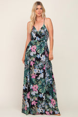 woman wearing a black floral maxi dress with colorful tropical patterns and a tie waist