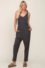 Woman wearing a charcoal grey ribbed sleeveless jumpsuit with pockets and olive green sandals