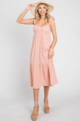 woman wearing a pink ruffled midi dress and straw sun hat with tan wedge sandals
