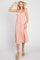 woman wearing a pink ruffled midi dress and straw sun hat with tan wedge sandals