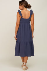 woman wearing a navy blue maternity dress with ruffle straps and a tiered skirt, showing her back
