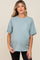 woman wearing a light blue maternity t-shirt with a pocket and rolled sleeves, showing her baby bump